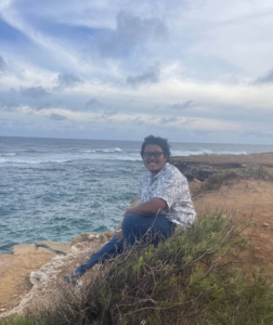 Owen sits in front of a beach view.